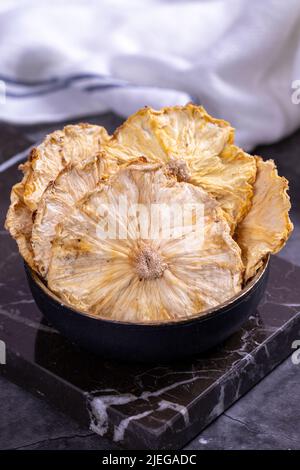 Dried pineapple slices. Sliced dried pineapple on dark background. Sun-dried fruit. close up Stock Photo