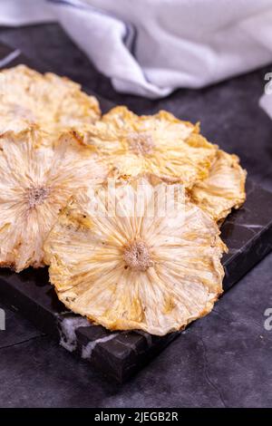 Dried pineapple slices. Sliced dried pineapple on dark background. Sun-dried fruit. close up Stock Photo