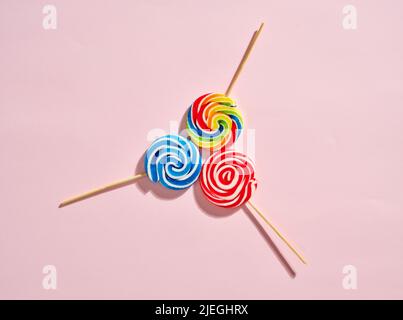 Colorful swirl round candy lollipops on pink background. Stock Photo