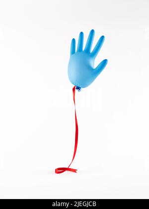 Blue flying inflated medical glove with red ribbon on white background. National doctors day concept. Stock Photo