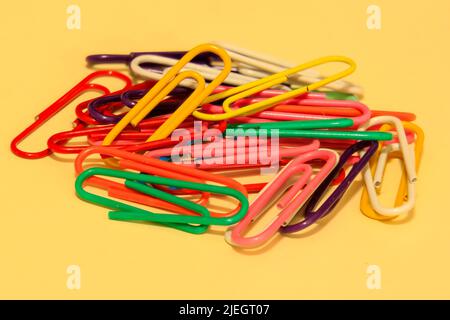 Extreme close up on a small group of colourful paper clips with a  a yellow background Stock Photo