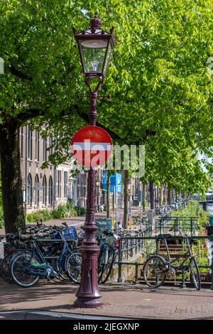 Stop sign in Amsterdam Netherlands Holland. Bikes parked on a canal bridge, traditional brick facade houses and paved streets Stock Photo