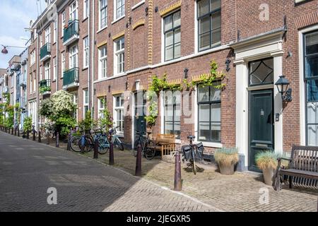 Amsterdam city paved pedestrian street. Traditional red brick wall houses and bicycles parked in front of the buildings, Holland Netherlands. Stock Photo