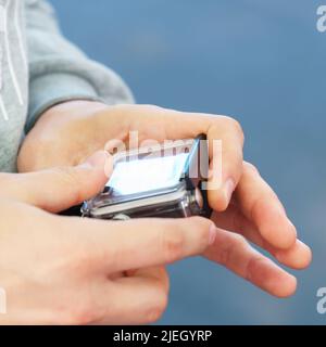 A man holds in his hands and looks through the footage on an action camera Stock Photo