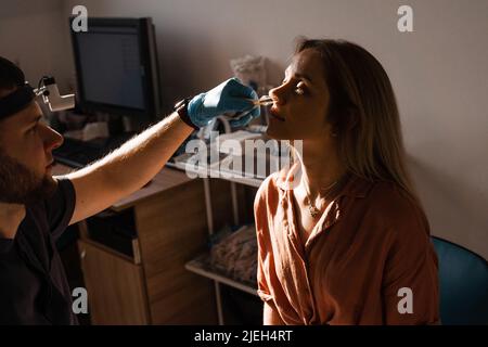 Rhinoscopy of woman nose. Consultation with doctor. Otolaryngologist examines girl nose before procedure of endoscopy of nose Stock Photo