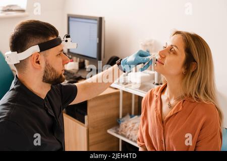 Rhinoscopy of woman nose. Consultation with doctor. Otolaryngologist examines girl nose before procedure of endoscopy of nose Stock Photo