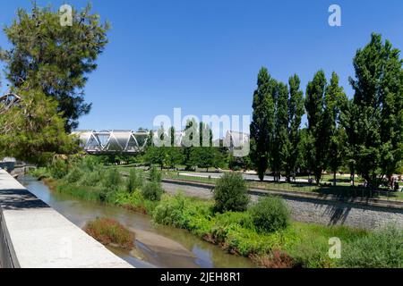 Madrid Rio Park. Views of the Madrid Río park next to the Manzanares river and green vegetation around it. Roads with bridges and footbridges. Stock Photo