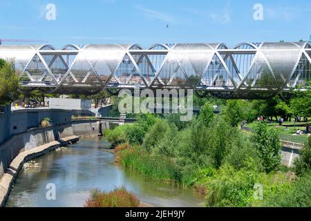 Madrid Rio Park. Views of the Madrid Río park next to the Manzanares river and green vegetation around it. Roads with bridges and footbridges. Stock Photo