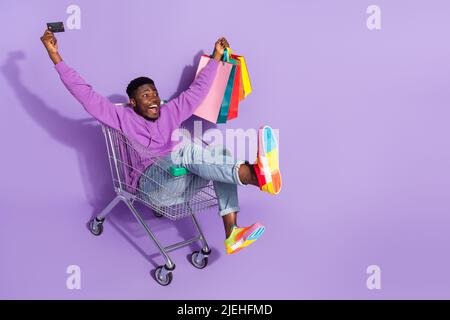 Full size photo of amazed funny guy hold packages debit card look empty space isolate don purple color background Stock Photo