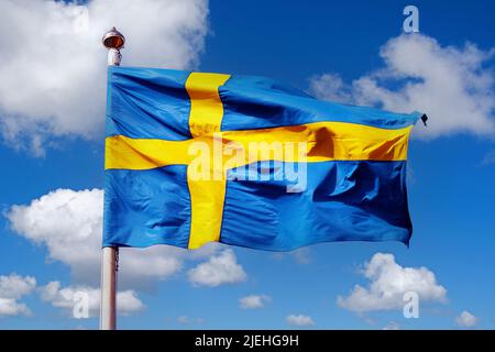 Die Nationalfahne von Schweden vor blauen Himmel mit Cumuluswolken Stock Photo