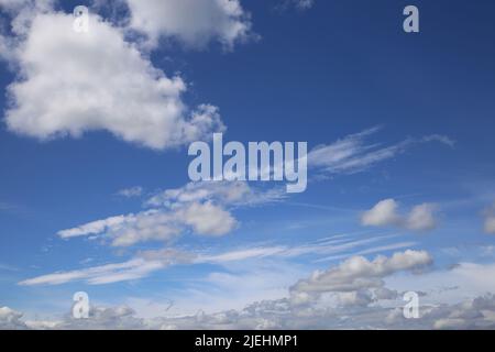 Dramatic blue clear summer sky background, white fluffy cumulus cloud over sea of cirrus clouds Stock Photo