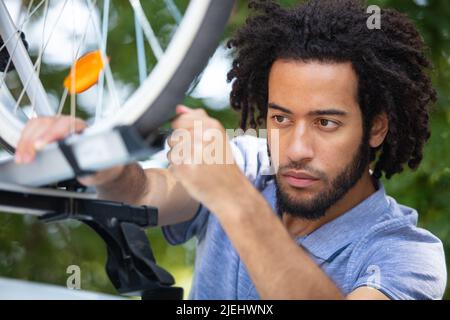 young man instals his mountain bike on the car roof Stock Photo
