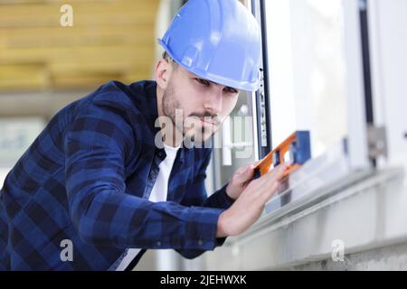 worker installs windows-master checks the level of the frame repair Stock Photo