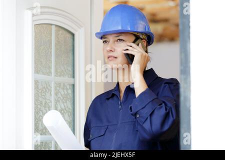 woman builder with blueprints using smart phone Stock Photo