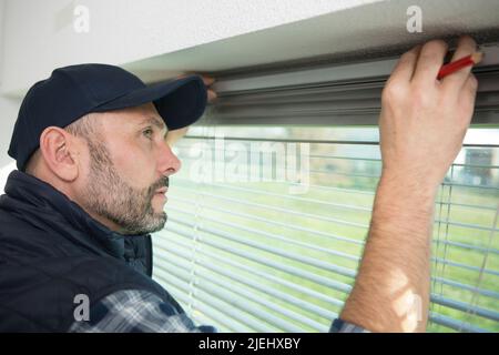 man measuring window prior to installation of shutter Stock Photo