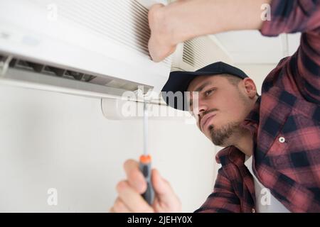 male technician installing outdoor air conditioning unit Stock Photo