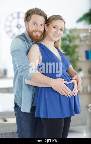happy pregnant couple hugging indoors Stock Photo