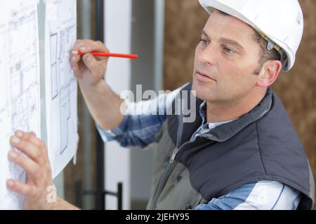 builder looking and hand writting on a plan Stock Photo