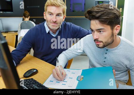male teacher and a student with a computer Stock Photo