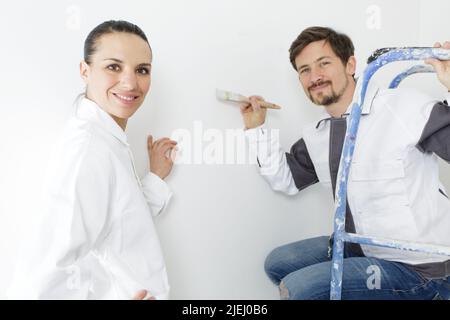 two young workers in uniform painting the wall Stock Photo