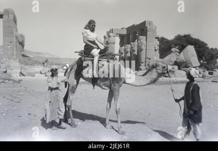 Egypt Luxor Upper Egypt Antiquities 1948 1940s B&W photos of Western tourists visiting historic sites White woman getting on and riding a camel Stock Photo