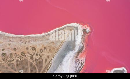 Flying over a pink salt lake. Salt production facilities saline evaporation pond fields in the salty lake. Dunaliella salina impart a red, pink water Stock Photo