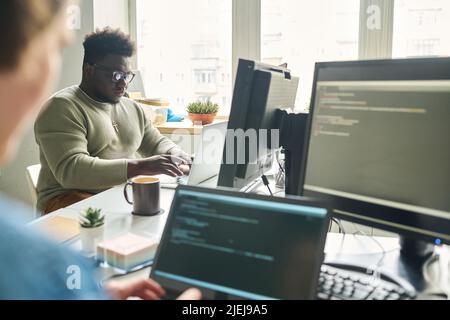 Programmers working at office desk with laptops writing codes for new software Stock Photo