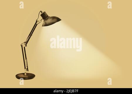 Illuminated vintage rusty desk lamp with flexible arms on a sepia background Stock Photo