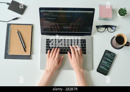 High angle view of developer programming language and program code on screen laptop working at table with smartphone and coffee drink Stock Photo