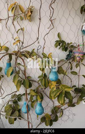 Blue bulbs and leaves hanging on a metallic wire on a white wall for decoration Stock Photo