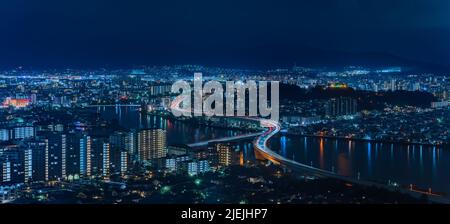 Bird's eye view of a night panorama cityscape of Fukuoka with the illuminated urban expressway circular route crossing in zig-zag the Muromi river tak Stock Photo