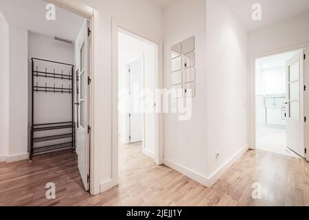 Distributor of a house with access to different rooms in a house with oak parquet floors and plain white painted walls Stock Photo