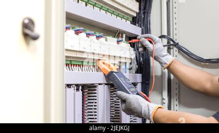 Electrical engineers check electrical control devices with a multimeter. Stock Photo