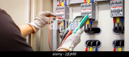Engineers working to inspect and maintain electrical control cabinets. Stock Photo