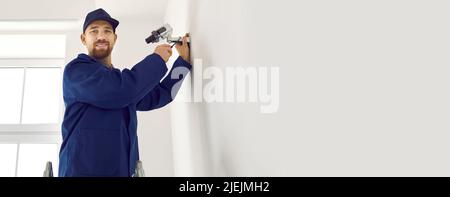 Professional young male technician installs surveillance camera inside office or apartment. Stock Photo