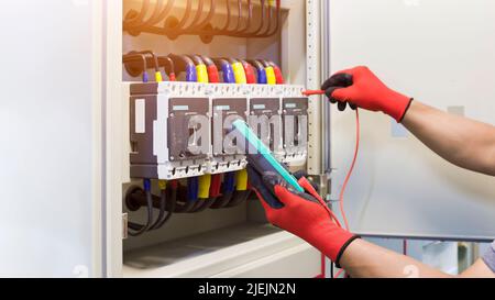 Electrical engineers check electrical control devices with a multimeter. Stock Photo