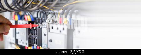 Electrical engineers check electrical control devices with a multimeter. Stock Photo