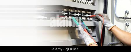 Electrical engineers check electrical control devices with a multimeter. Stock Photo