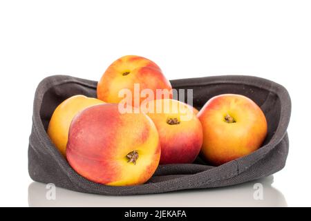 Several juicy organic nectarines in a linen basket, close-up, isolated on a white background. Stock Photo