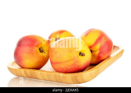 Several juicy organic nectarines on a wooden tray, close-up, isolated on a white background. Stock Photo