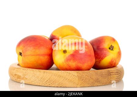 Several juicy organic nectarines on a wooden tray, close-up, isolated on a white background. Stock Photo