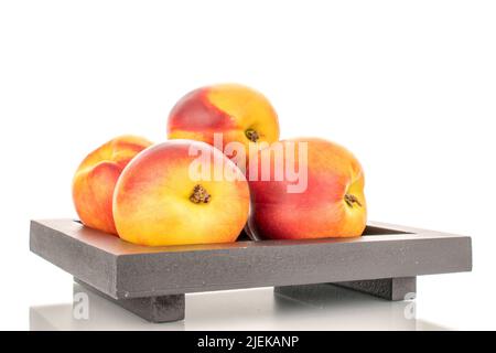 Several juicy organic nectarines on a wooden tray, close-up, isolated on a white background. Stock Photo