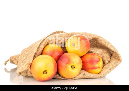 Several juicy organic nectarines with a jute bag, close-up, isolated on a white background. Stock Photo