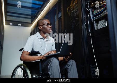 Portrait of young man with disability working as IT technician and managing server network, copy space Stock Photo