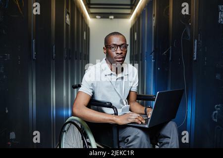 Portrait of African American man using wheelchair working as IT technician in server room Stock Photo