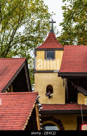 Bavarian village of Helen, Georgia narrow alley traditional architecture colorful yellow building house and red roof church cross tower vertical view Stock Photo