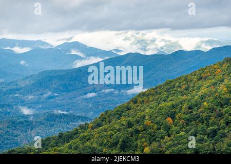 High angle aerial view from overlook on Blue Ridge Cowee mountains parkway in North Carolina with layers of mist and fog on cloudy day and fall leaf f Stock Photo
