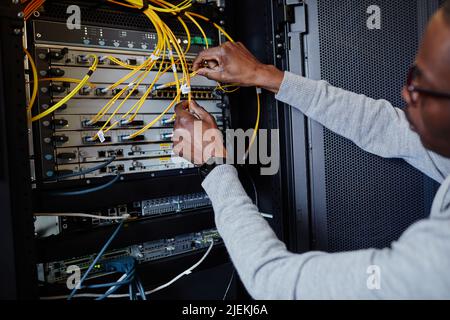Close up of IT engineer connecting cables in server room while setting up data network, copy space Stock Photo