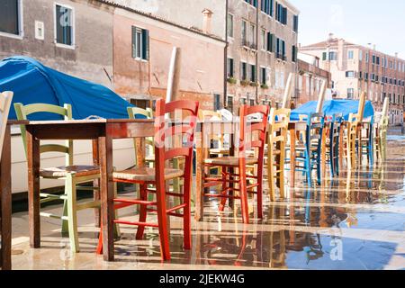 Colorful chairs in a row along Venetian canal. Venice landscape, Italy Stock Photo