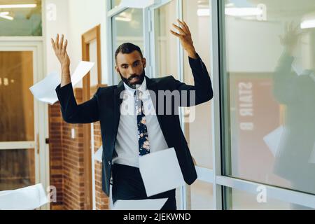 Business stress overwhelmed African American businessman throwing papers in the air office shot Stock Photo